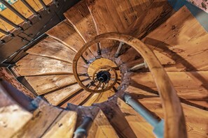 Una escalera de caracol con escalones de madera y barandilla metálica central.