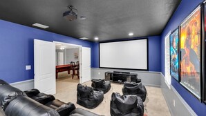 Ein Heimkinozimmer mit einer großen Leinwand, bequemen Sitzen und einem Projektor.