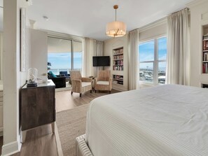 Ein Hotelzimmer mit einem großen Bett, einem Schreibtisch, einem Fernseher, einem Bücherregal und Blick auf die Stadt.