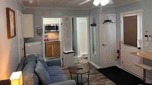 A compact living space with a kitchenette, a ceiling fan, and a door leading to another room.
