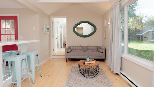 A modern living room with a grey sofa, a round coffee table, and a large window with curtains.