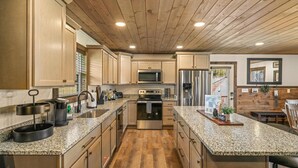 Une cuisine moderne dotée de plans de travail en granit, d’appareils électroménagers en acier inoxydable et de meubles en bois.