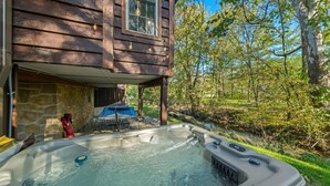 A hot tub outside a wooden house with a stone wall, a hammock, and a small pool. - Creekside Cabin Smoky Mtn Views Arcade HotTub Pet (Sevierville)