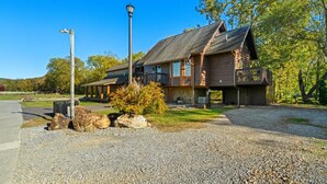 A two-story log cabin with a stone foundation, a covered porch, and a deck. - Creekside Cabin Smoky Mtn Views Arcade HotTub Pet (Sevierville)