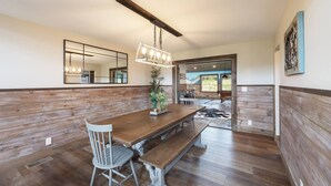 A dining area with a wooden bench, a table, and chairs. There is a mirror on the wall and a hanging light fixture. - Family Retreat - Pool, Game Room, Theatre, Bowling (Sevierville)