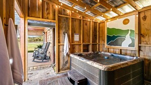 A wooden cabin with a hot tub, a chair, and a painting of a landscape. - Cozy Honeymoon Cabin w/ Mtn Views-Hot Tub-Fire Pit (Sevierville)