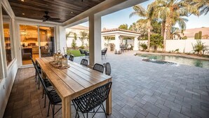 A covered patio with a wooden table and chairs, a pool, and outdoor furniture. - 4br, 3ba, pool near TPC in Scottsdale (Scottsdale)