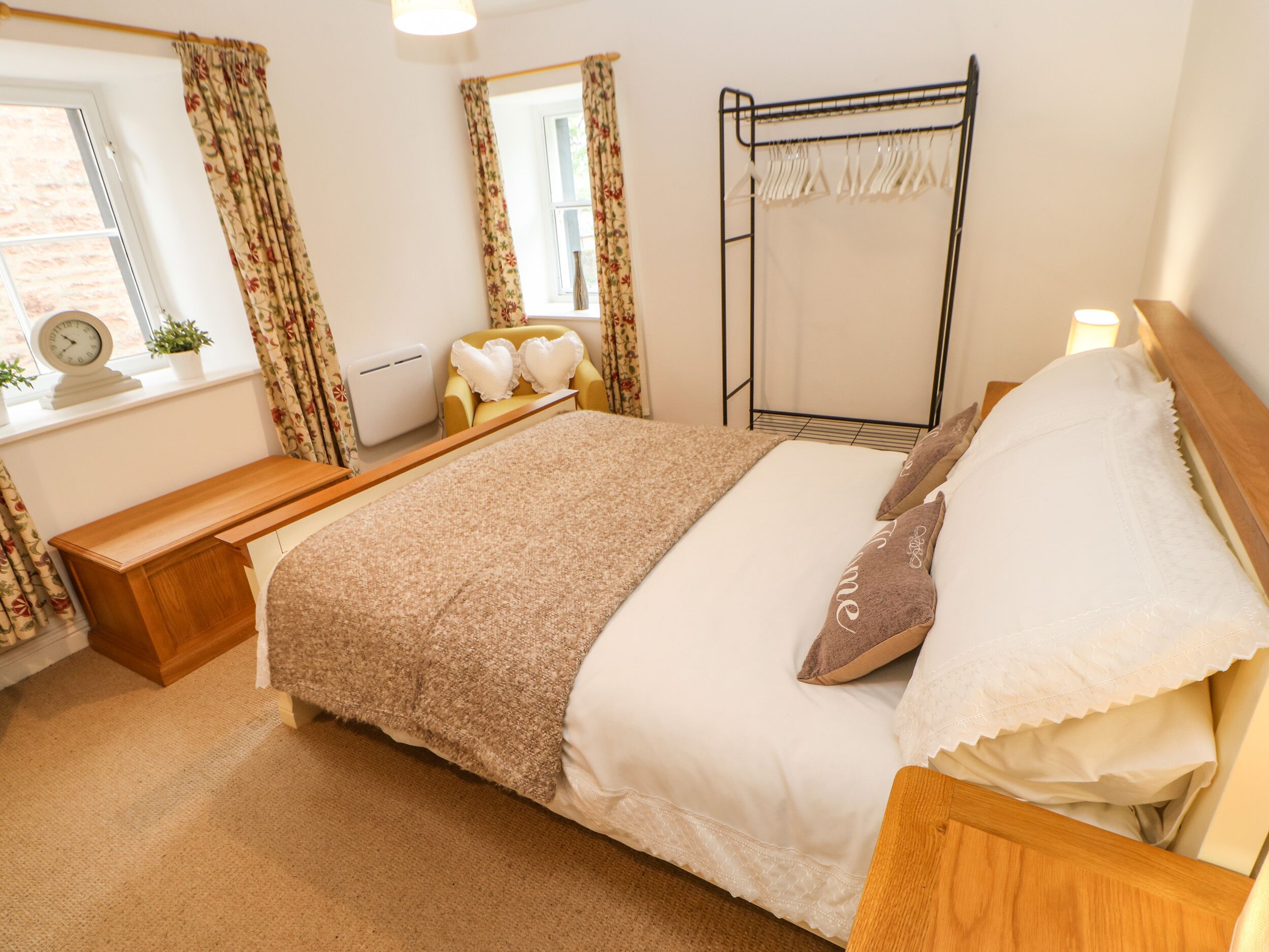 A bedroom with a bed, bedside table, and a window with curtains.