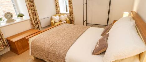 A bedroom with a bed, bedside table, and a window with curtains.