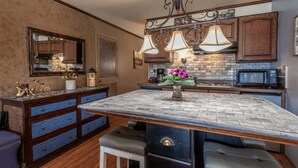 A kitchen with a large island, wooden cabinets, a microwave, and pendant lighting. - Waterfront studio w/private balcony & stunning views - Marina Cay Vista Aqua Studio (Bigfork)