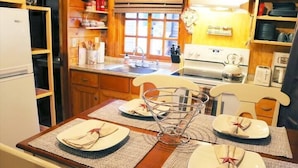 A wooden dining table set with plates, napkins, and a metal basket.