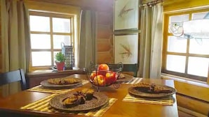 Een houten eettafel met placemats, een schaal met fruit en borden klaar voor een maaltijd.