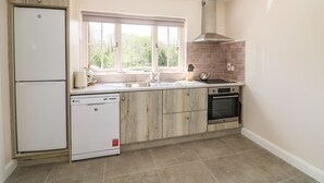 A kitchen with a double-door refrigerator, a dishwasher, a stove, and a window with a view of greenery. - Yew Tree House (Ballindaggan)