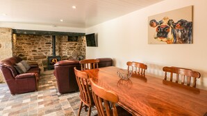 A cozy dining area with a wooden table and chairs, a stone fireplace, and a painting on the wall. - Yew Tree House (Ballindaggan)