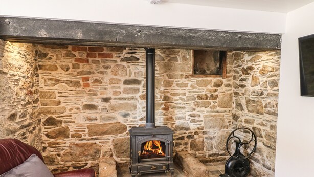 A stone fireplace with a black chimney, a red leather sofa, and a black kettle. - Yew Tree House (Ballindaggan)