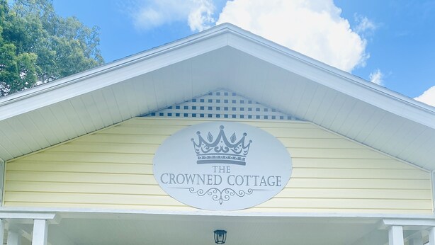 En byggnad med en skylt som visar texten ”The Crowned Cottage” och siffrorna ”Six Twenty” på dörren.
