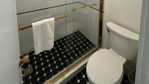 A modern bathroom with a glass-enclosed shower, a white toilet, and a black and white tiled floor. - Maple Leaf Inn - Lake Placid (Lake Placid)