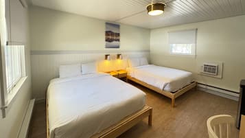 A room with two beds, a ceiling light, a window with blinds, and a wall-mounted air conditioner.