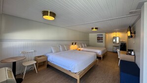A compact hotel room with two single beds, a small desk, a chair, a table, and a kitchenette. - Maple Leaf Inn - Lake Placid (Lake Placid)