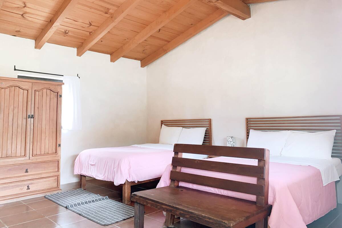 Un dormitorio con dos camas, muebles de madera y un ventilador de techo.
