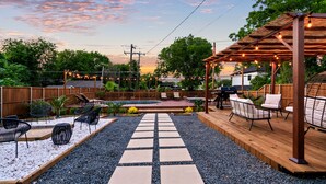 Eine Terrasse mit Sitzgelegenheiten, eine Pergola mit Lichterketten und ein Poolbereich.