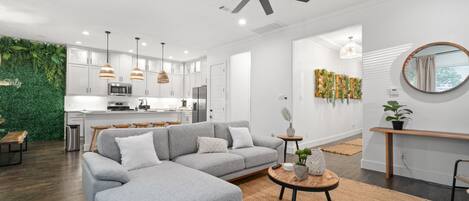 A modern living room with a grey sectional sofa, a round coffee table, and a ceiling fan.