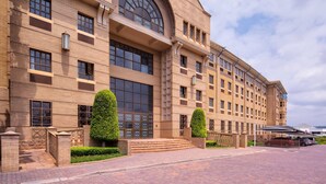 A large, multi-story building with a symmetrical facade, large windows, and a prominent arched entrance. - The Archer Aparthotel by Totalstay (Sandton)