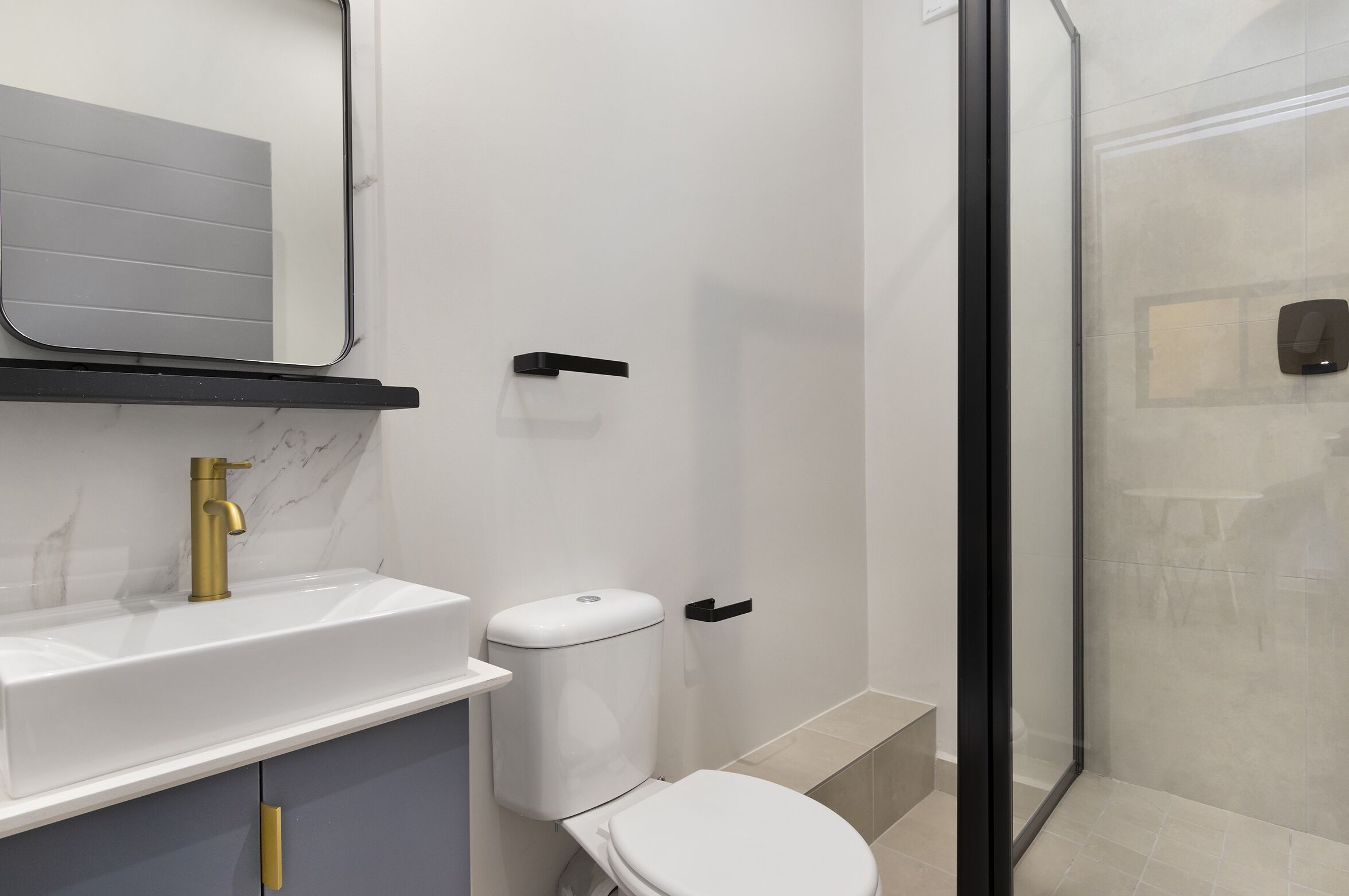 Une salle de bain moderne avec un lavabo blanc, un robinet doré et des toilettes.