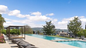A swimming pool with lounge chairs and a pergola, surrounded by trees and buildings in the background. - The Archer Aparthotel by Totalstay (Sandton)