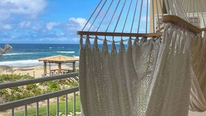 Una hamaca en un balcón con vista a una playa y una visión despejada del océano.