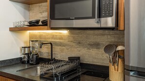 A modern kitchen with wooden cabinets, a stainless steel microwave, a built-in dishwasher, and a coffee maker. - BoHo lofts & studios new modern w/ ocean-view pool (Playa del Carmen)