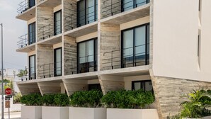 A modern multi-story building with balconies, large windows, and a flat roof with greenery. - BoHo lofts & studios new modern w/ ocean-view pool (Playa del Carmen)