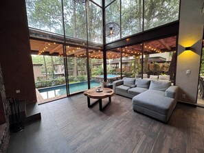 A modern living room with large windows, a pool, and a cozy seating area.