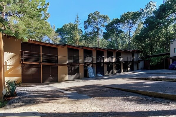 A building with multiple garage doors, a gravel driveway, and trees in the background.
