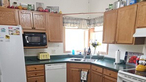 A compact kitchen with wooden cabinets, a microwave, a refrigerator, a dishwasher, and a stove. - Grandma's House in the Woods, 3/4 mile to Custer (Custer)
