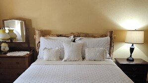 A neatly made bed with a quilted cover, a wooden headboard, and two bedside tables with lamps. - Grandma's House in the Woods, 3/4 mile to Custer (Custer)