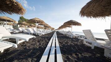 On the beach, black sand, beach umbrellas, beach towels