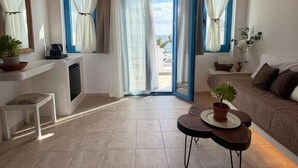 Una habitación con techo de madera, un sofá, una mesita con una planta y vistas a través de un ventanal.