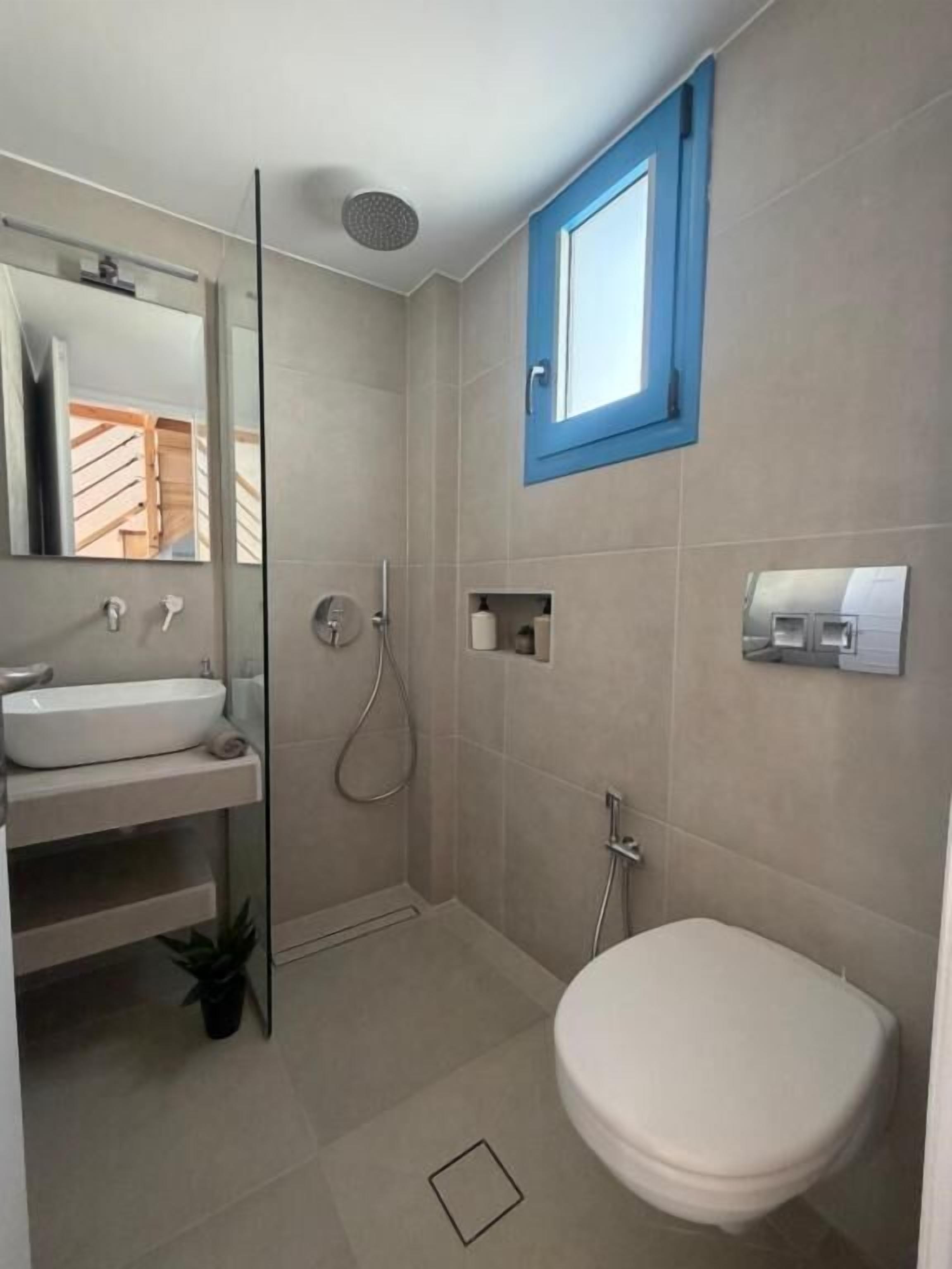 Ein Badezimmer mit Toilette, Waschbecken, Dusche und einem Fenster.
