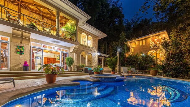 A luxurious pool area with a large, clear pool, surrounded by potted plants and outdoor seating. - Casa Bamboo with Guest House | Colonial Estate | Sleeps 14 | Manuel Antonio (Manuel Antonio)