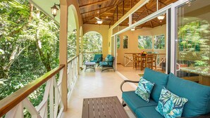 A covered outdoor area with a wooden ceiling, a sofa with patterned cushions, and a dining table with chairs. - Casa Bamboo with Guest House | Colonial Estate | Sleeps 14 | Manuel Antonio (Manuel Antonio)