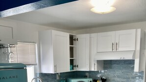 A kitchen with white cabinets, a teal refrigerator, and a microwave. - MiCasitAzul, 10:00 AM checking, Luxury Patio, BBQ and Free Parking. (Miami)