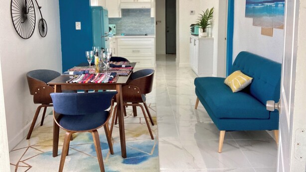 A dining area with a table set for four, a blue sofa, and a ceiling fan. - MiCasitAzul, 10:00 AM checking, Luxury Patio, BBQ and Free Parking. (Miami)
