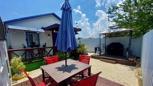 A patio area with a wooden table and red chairs, a blue umbrella, and a barbecue grill. - MiCasitAzul, 10:00 AM checking, Luxury Patio, BBQ and Free Parking. (Miami)
