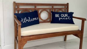 A wooden bench with two cushions, one with "Welcome" and the other with "Be Our Guest". - MiCasitAzul, 10:00 AM checking, Luxury Patio, BBQ and Free Parking. (Miami)