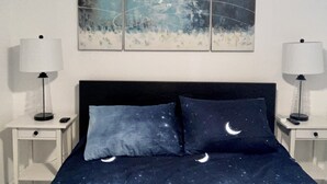 A bedroom with a bed, two bedside tables, two lamps, and a wall-mounted abstract painting. - MiCasitAzul, 10:00 AM checking, Luxury Patio, BBQ and Free Parking. (Miami)