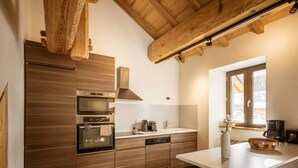 A modern kitchen with wooden cabinetry, stainless steel appliances, and a window providing natural light. - Duplex 5 rooms for 10 people, pets allowed, balcony, parking (Valloire)