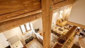 A modern kitchen with wooden beams, a dining area with a yellow sofa, and a view of the living room. - Duplex 5 rooms for 10 people, pets allowed, balcony, parking (Valloire)