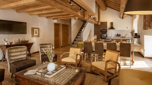 A spacious living room with a wooden ceiling, a fireplace, and a dining area with a kitchen in the background. - Duplex 5 rooms for 10 people, pets allowed, balcony, parking (Valloire)