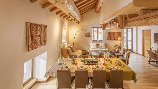 A spacious dining area with a high wooden ceiling, a long table set for a meal, and a cozy seating area with a sofa and chairs. - Duplex 5 rooms for 10 people, pets allowed, balcony, parking (Valloire)